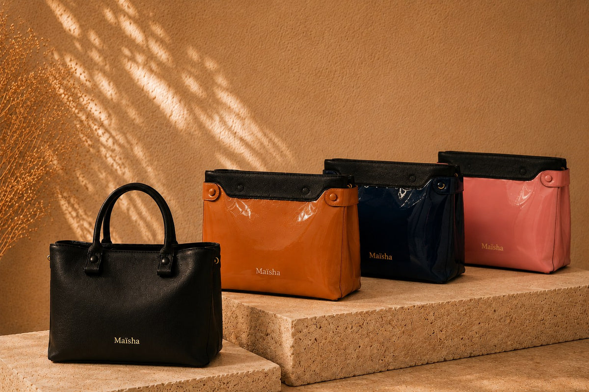 Cabas Maïsha noir en cuir avec ses pochettes vernies caramel, bleu marine et rose alignées sur de la pierre travertin